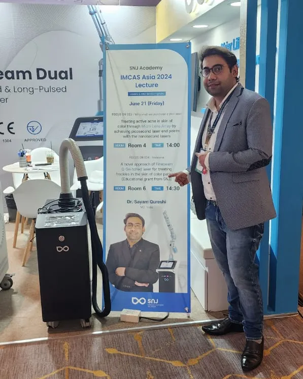 Dr. Sayam Qureshi la standul SNJ de la IMCAS Asia 2024, lângă afișul prelegerilor sale și un laser SNJ